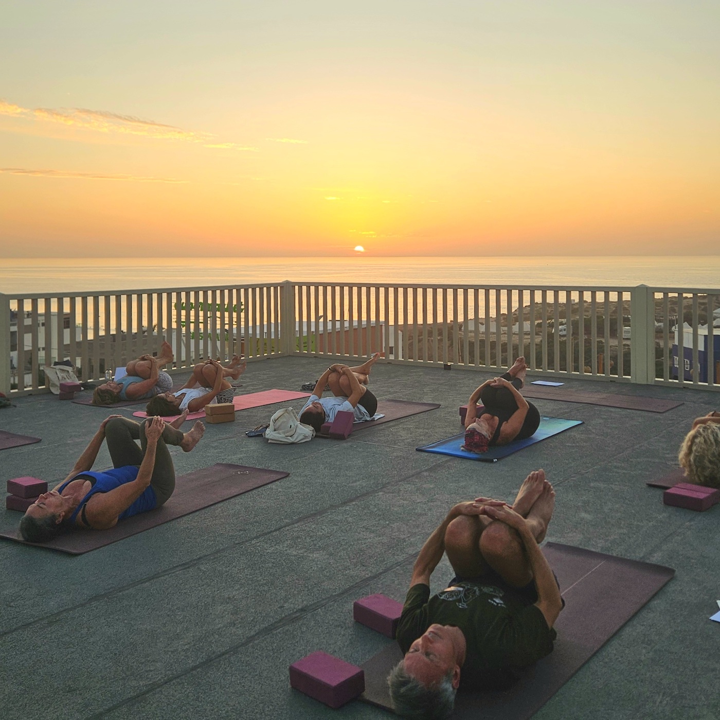 Ines leading a yoga class on a rooftop terrace whilst the sun sets on her Moroccan surf camp in the Summer