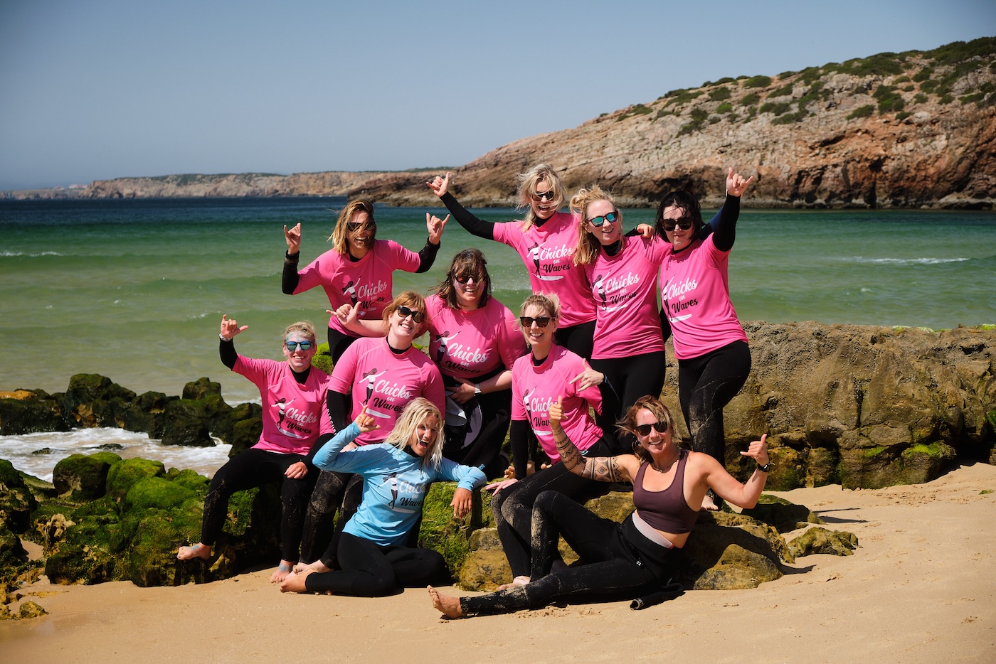 A group on a female founded spaces surfing retreat. All waving at the camera